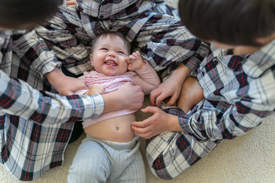 A group of people playing with a baby on the floor.