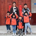 A group of children posing for a picture in front of a door.