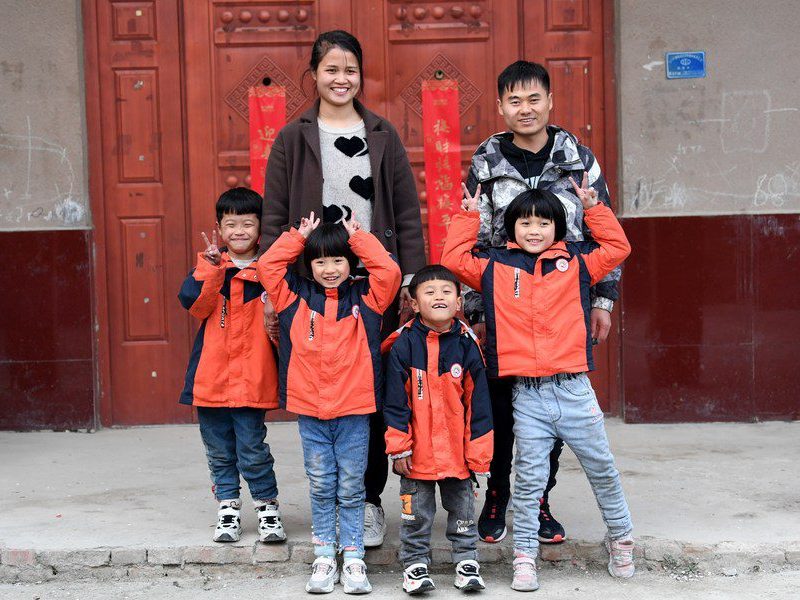 A group of children posing for a picture in front of a door.