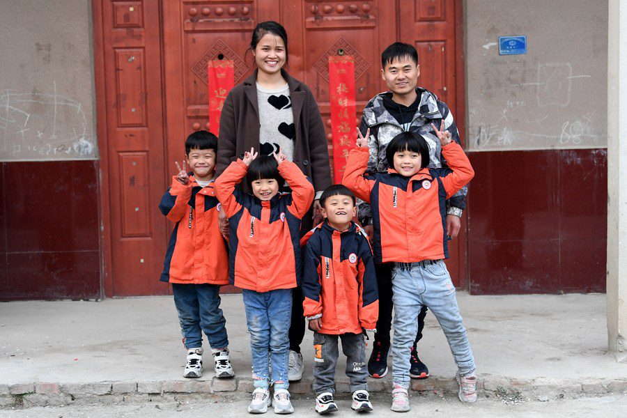 A group of children posing for a picture in front of a door.