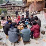 A group of people sitting around a table in a village.