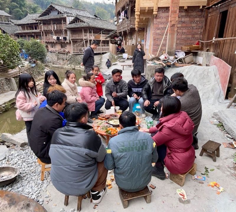 A group of people sitting around a table in a village.