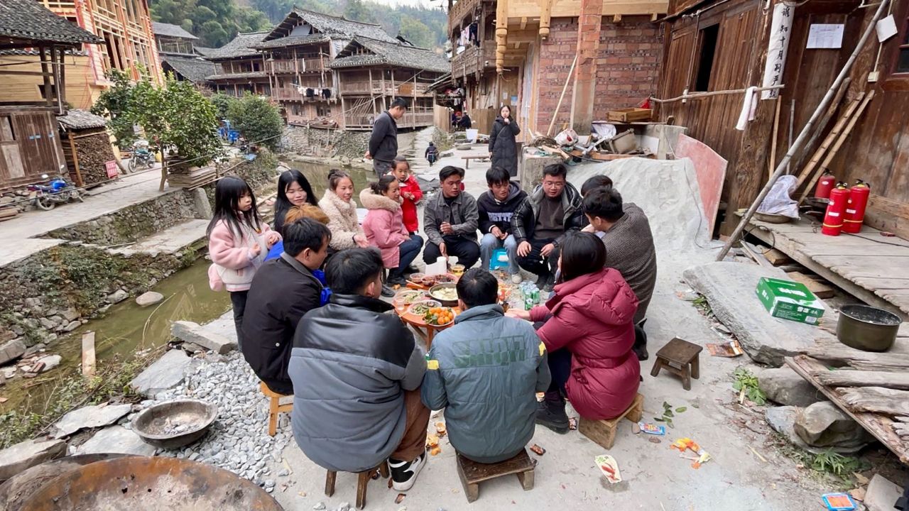 A group of people sitting around a table in a village.