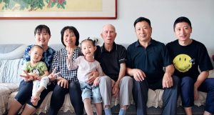 A family sits on a couch and poses for a photo.