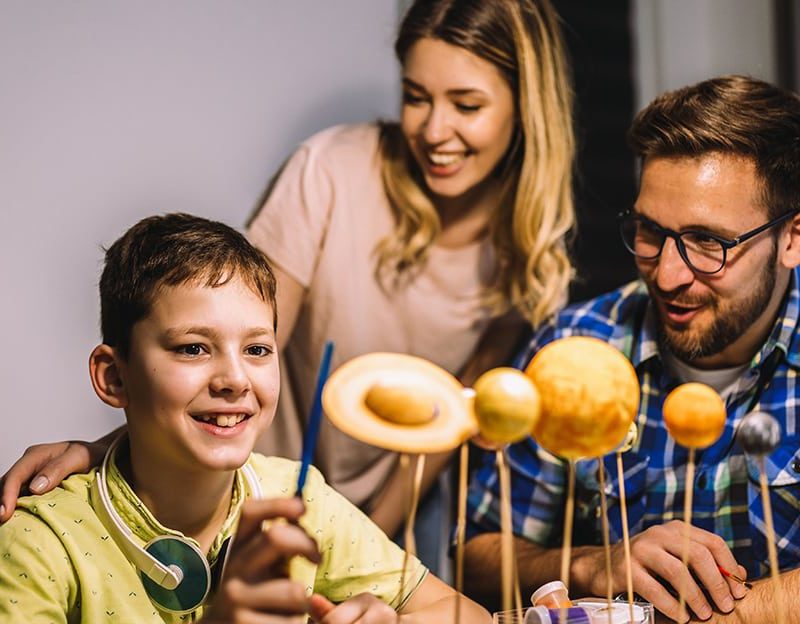 A family is sitting at a table and making doughnuts.