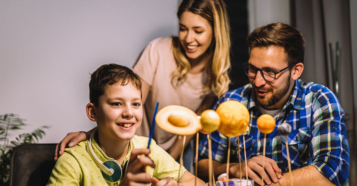 A family is sitting at a table and making doughnuts.