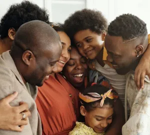 A family is hugging each other in front of a white background.