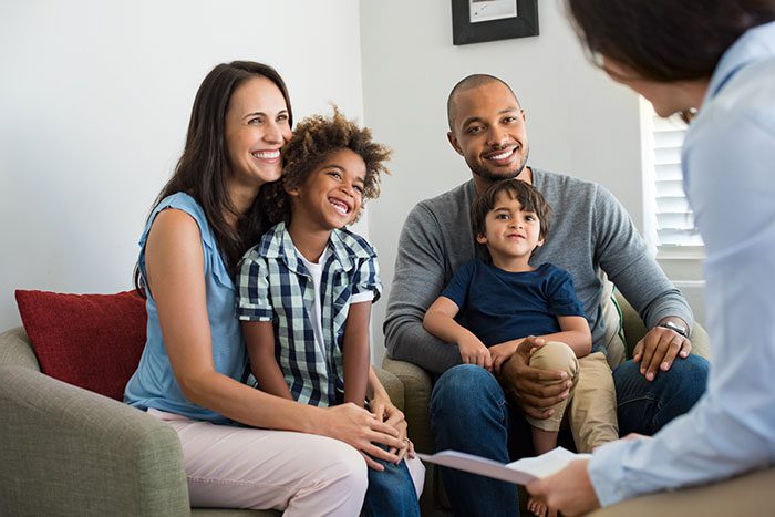 A family sits on a couch while a counselor talks to them.