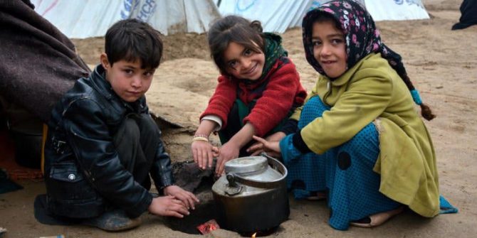 Iraqi refugee children cook in front of tents.