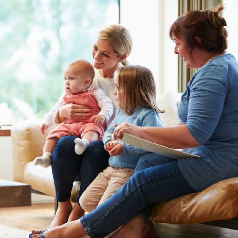 A group of women sitting on a couch with their children.