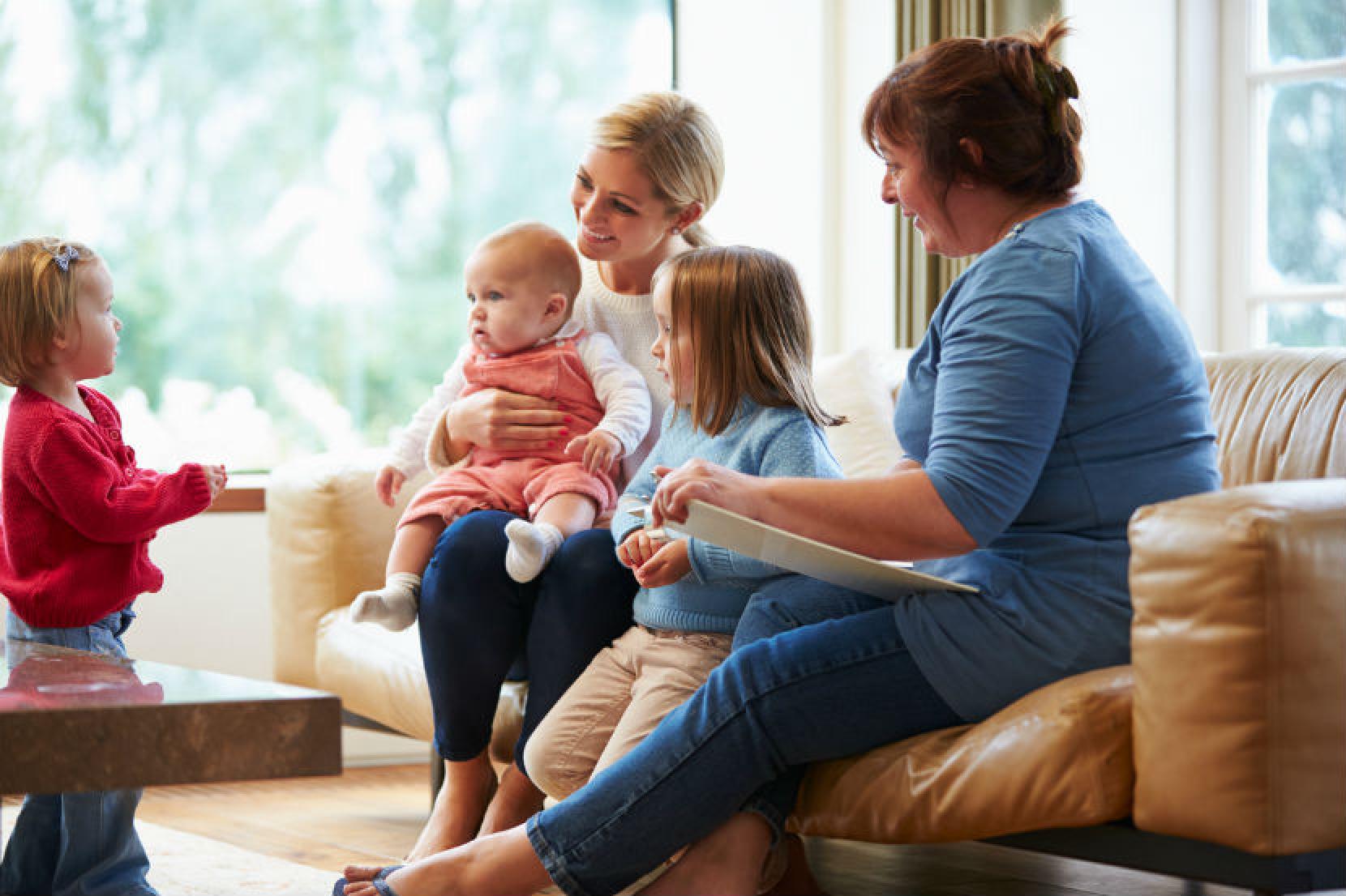 A group of women sitting on a couch with their children.