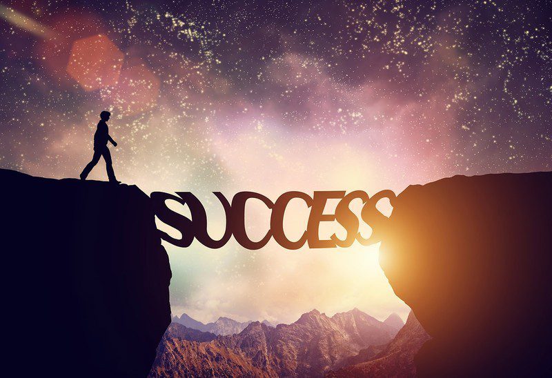 A man walking across a cliff with the word success.