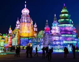 Ice sculptures are lit up in front of a castle.